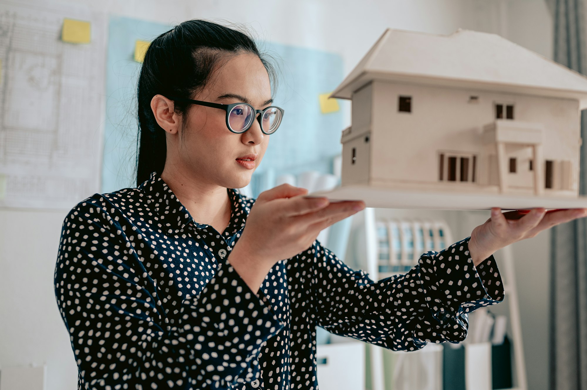 Young female architect is looking on the new model in the industrial space with big factory